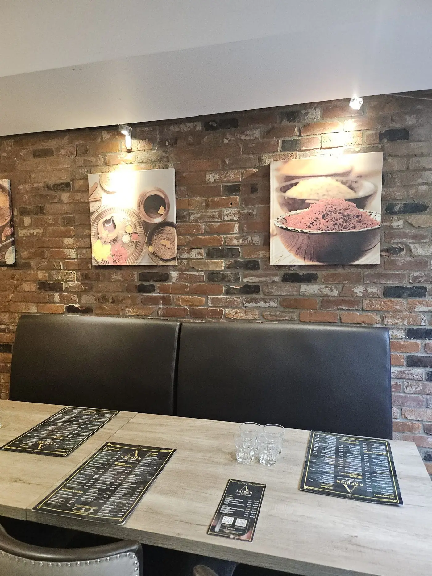 Exposed-brick dining nook with framed art at Aafrien Indian Restaurant, Toronto
